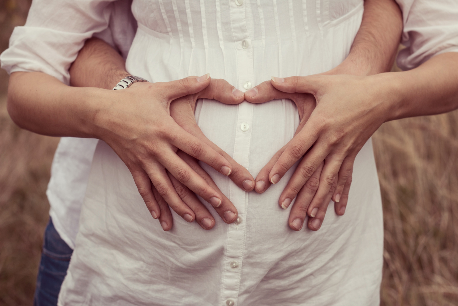 Pregnant Couple Making Heart Shaped Gesture on Belly